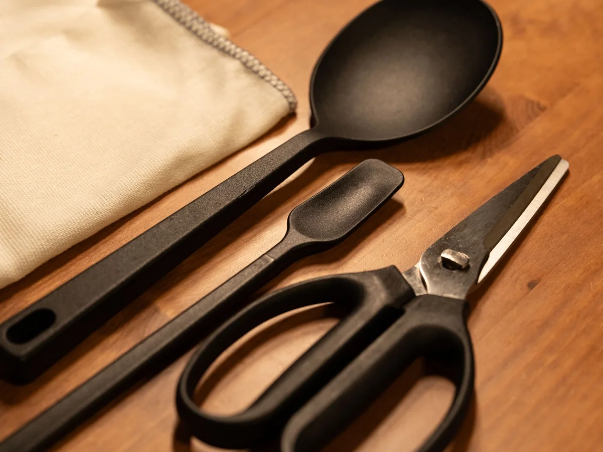 Black kitchen utensils and scissors on a wooden worktop