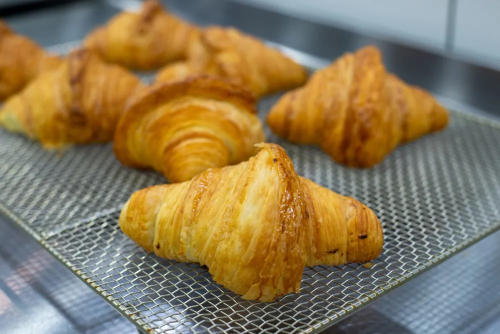 Flaky all-butter croissants on a wooden board