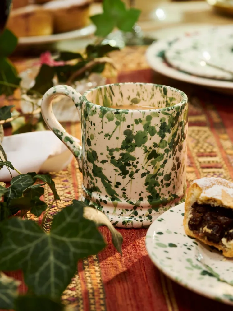 A cream Emma Bridgewater mug splattered with green paint