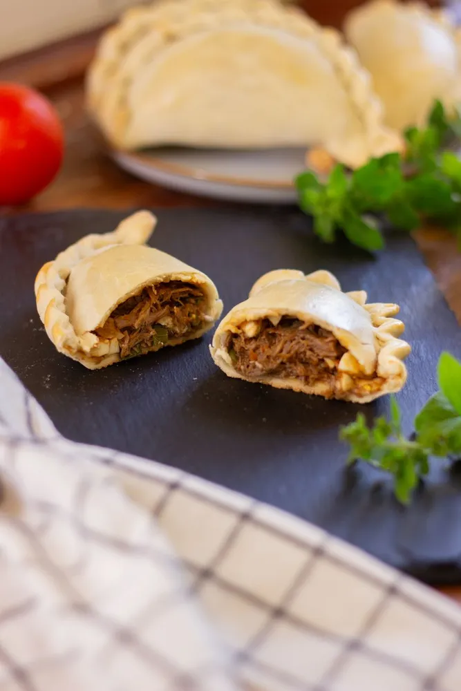 Baked pasties, one cut open to show the beef filling